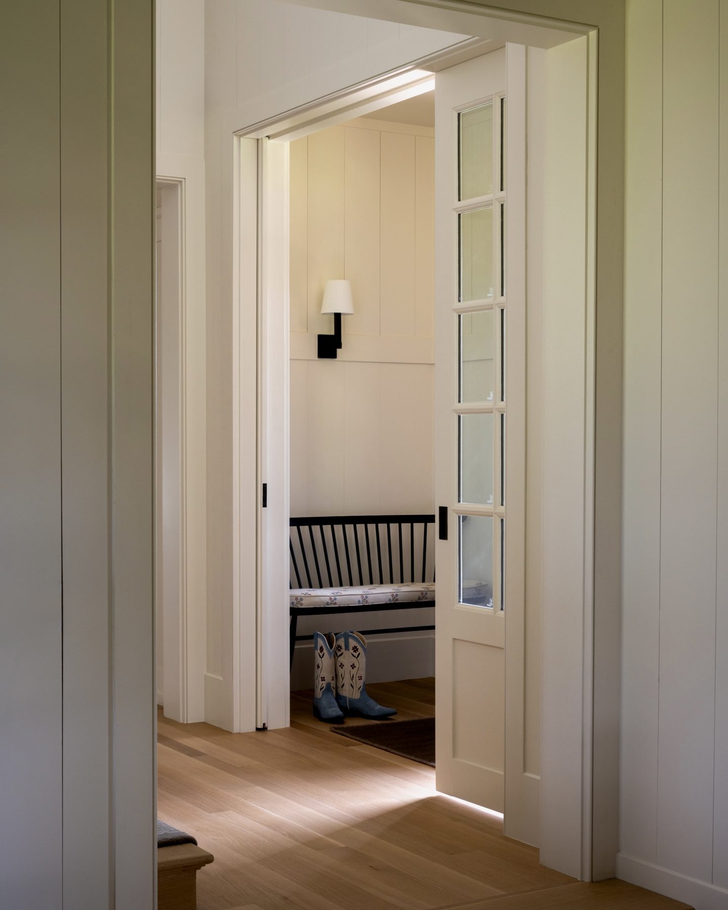 A pair of pocket doors open to a small bench nook, with embroidered cowboy boots waiting on the floor.