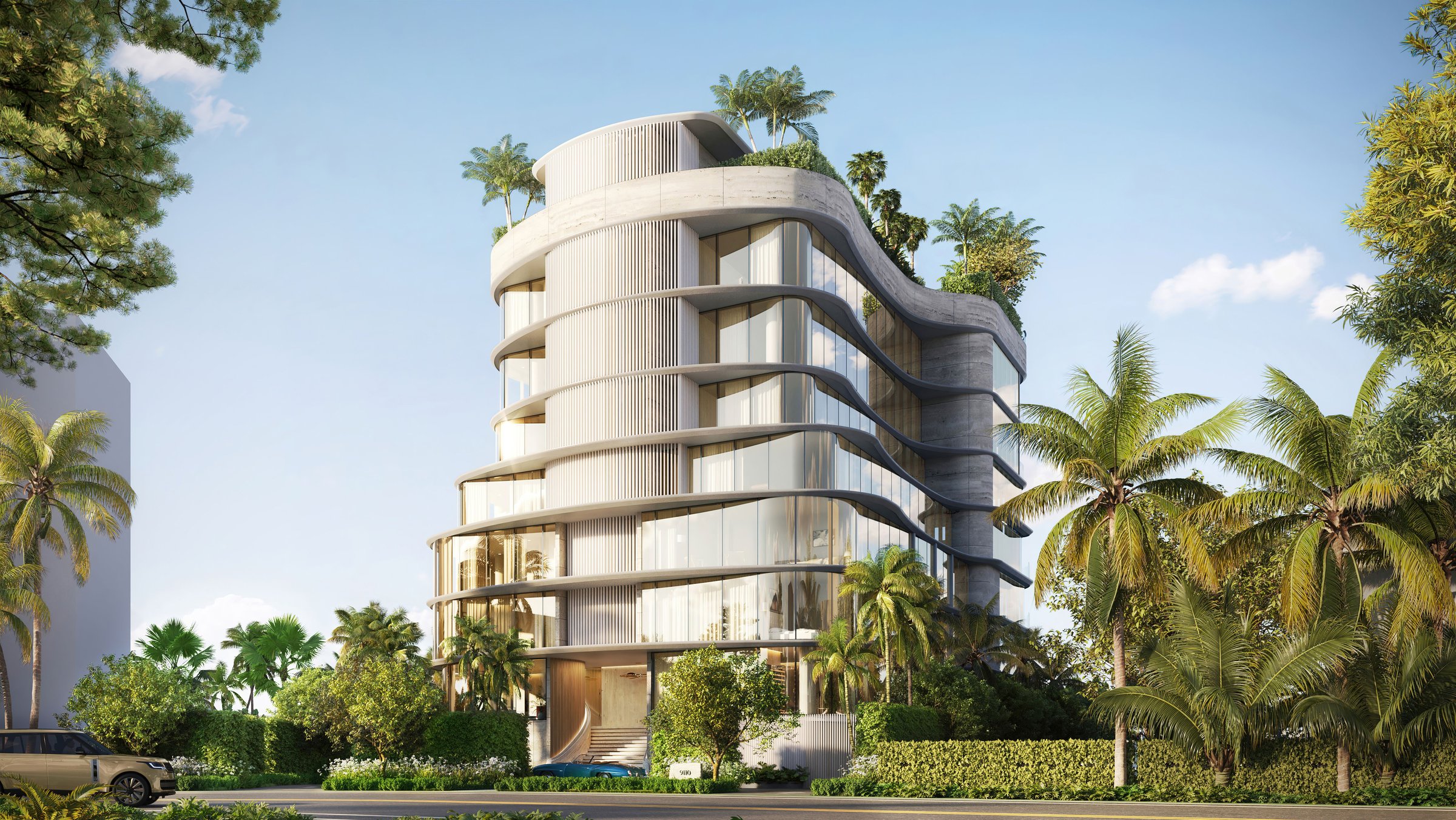 Curved white residential building with glass balconies and rooftop palm landscaping, framed by mature palm trees on a Miami street.