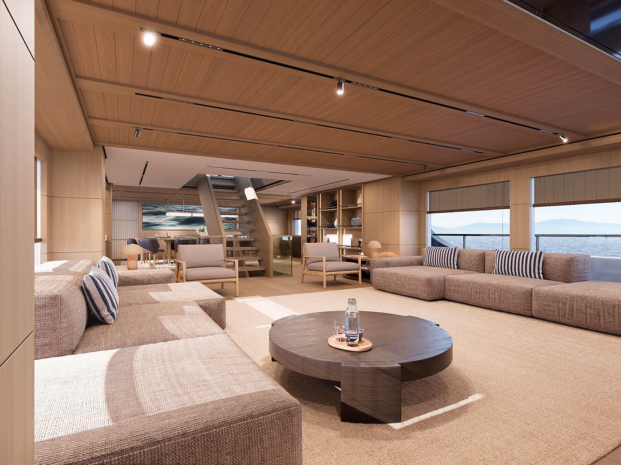 Open salon with two facing sectional sofas, a dark round coffee table, and a wave photograph above the staircase.