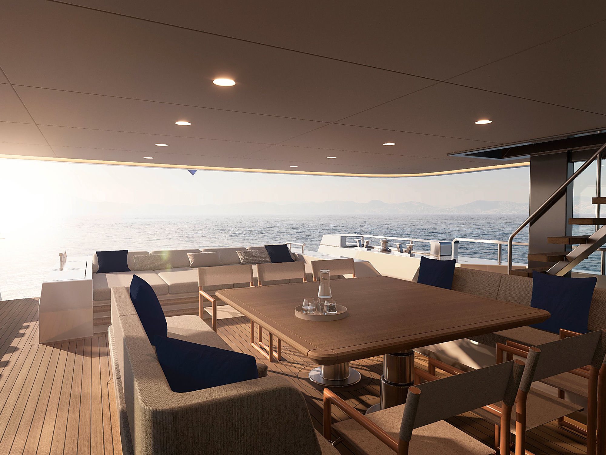 Aft deck dining table set at sunset, with navy cushions and open water glowing gold beyond the rail.
