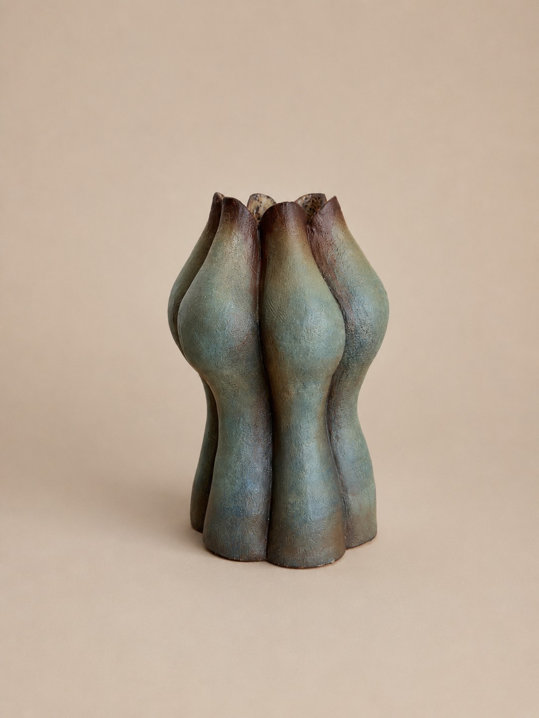 Ceramic vessel by Loriann Stevenson with fluted, petal-like forms in a mottled sage and oxblood glaze.