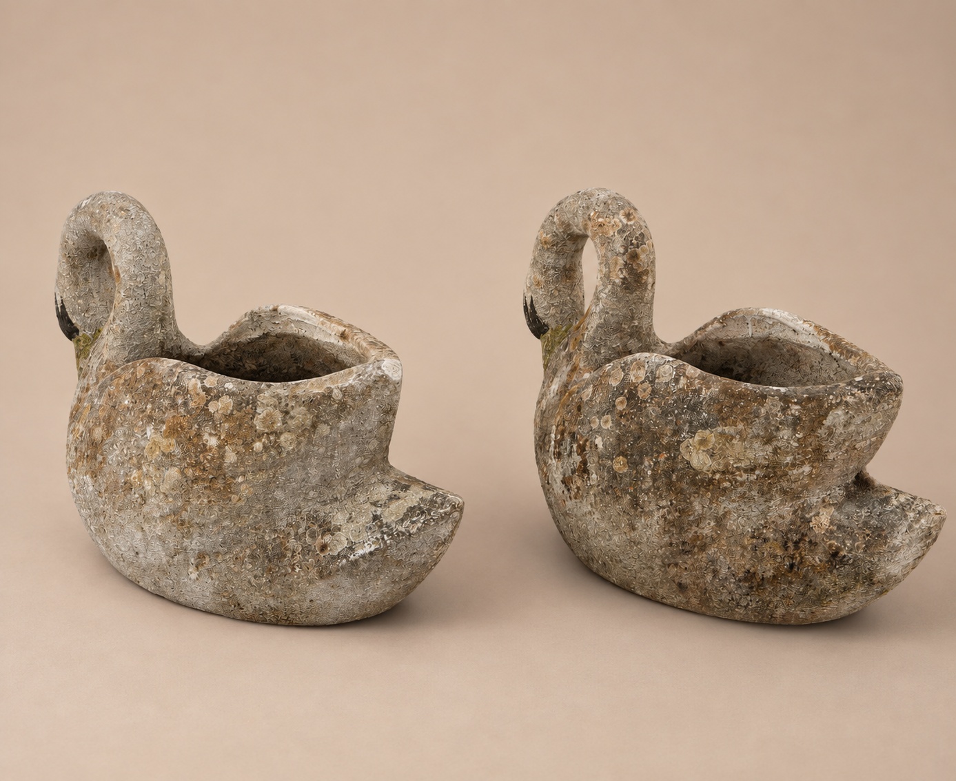 Rear view of the two vintage concrete swan planters, showing the curved tail forms and open basket backs.